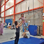 young child on a trapeze with the help of a NECCA coach