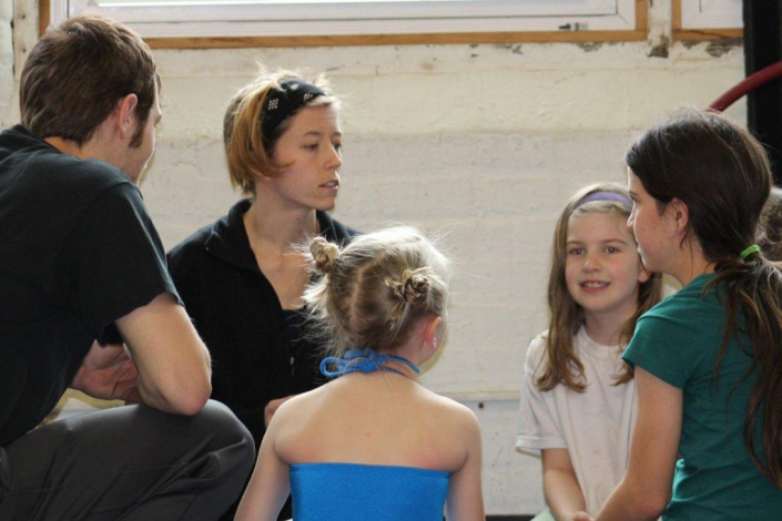 photo of a NECCA coach speaking with several young students