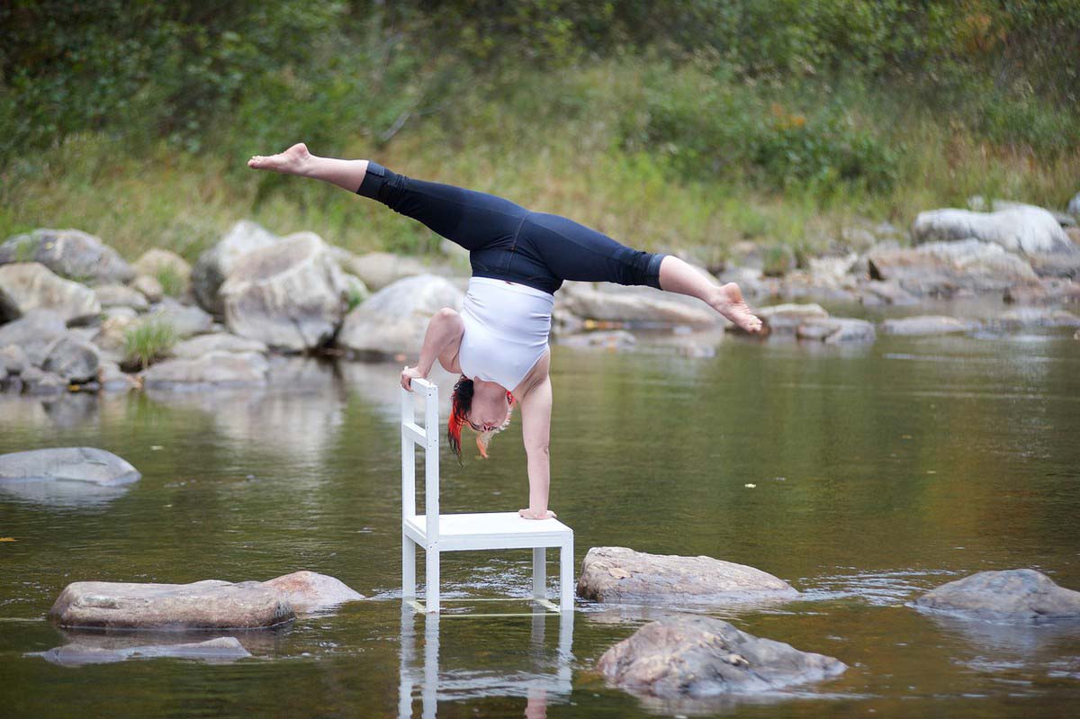 marysia walczers doing a handstand on a chair in a river